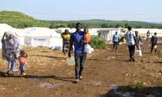 Displaced Sudanese who have returned from Ethiopia, carry gallons of water in a camp run by the United Nations Refugee Agency (UNHCR) in Sudan
