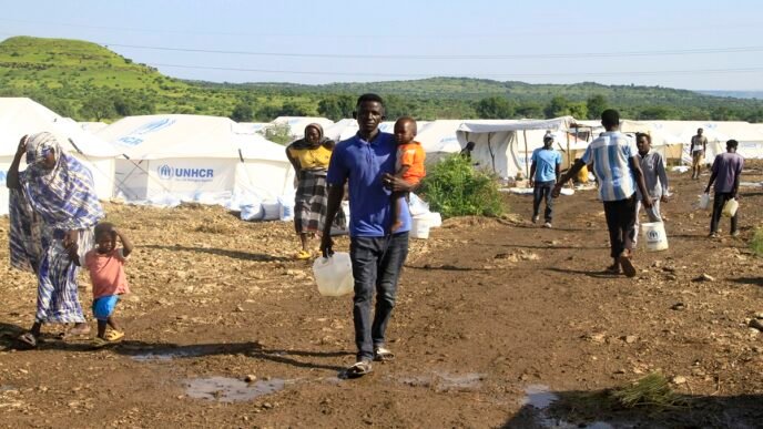 Displaced Sudanese who have returned from Ethiopia, carry gallons of water in a camp run by the United Nations Refugee Agency (UNHCR) in Sudan