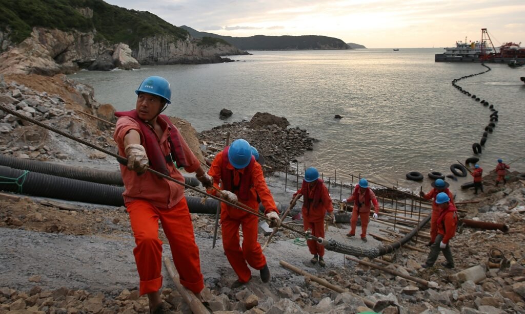 Workers lay submarine cables at an offshore wind farm in Zhoushan, East China