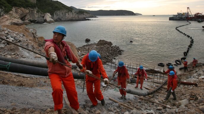 Workers lay submarine cables at an offshore wind farm in Zhoushan, East China