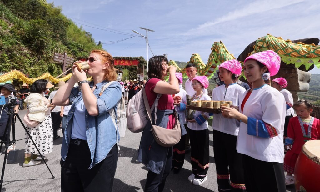 Foreign visitors taste local drinks during the Terraced Fields Plowing Festival held in Guilin, South China